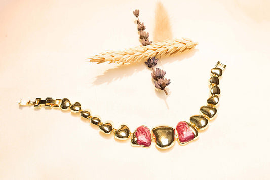 Elegant heart-link bracelet in gold plating with glossy red gemstone details, ideal for everyday or special occasions.