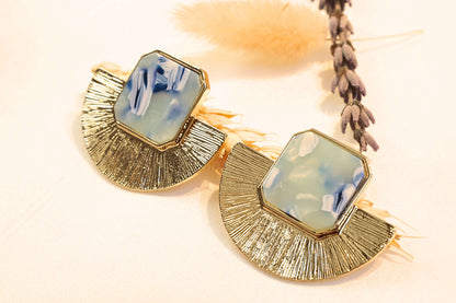 Elegant gold-plated earrings featuring a striking blue resin stone, ideal for chic outfits.