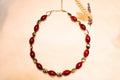 Bohemian-style gold-plated necklace with red stone effect.