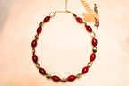 Bohemian-style gold-plated necklace with red stone effect.