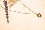Dainty gold chain necklace featuring a sunburst pendant with a warm center stone for a unique boho-chic vibe.