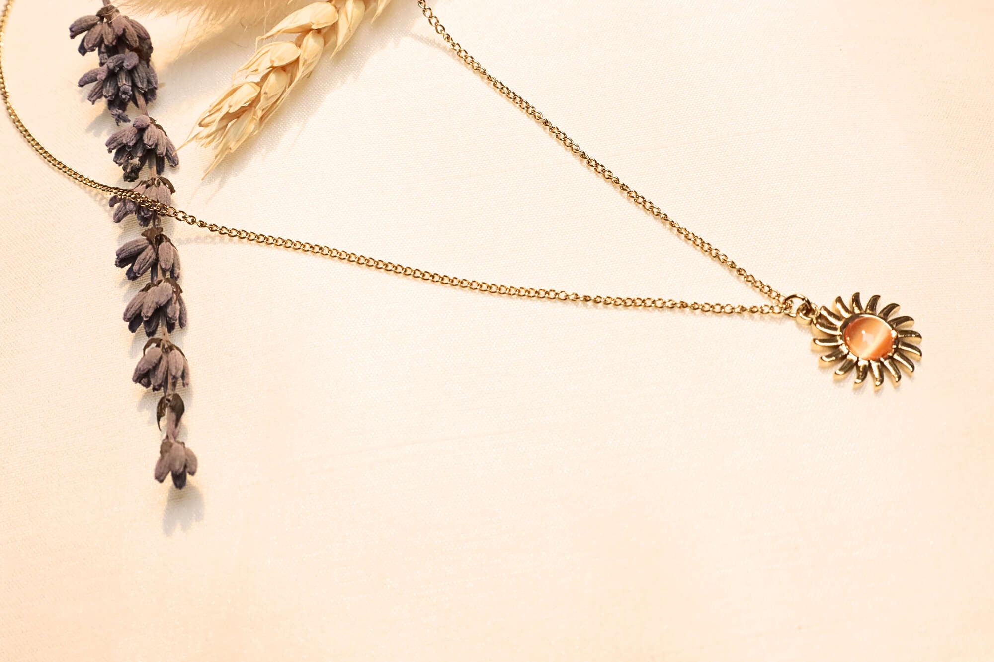 Dainty gold chain necklace featuring a sunburst pendant with a warm center stone for a unique boho-chic vibe.