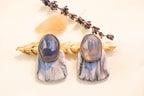 Close-up of statement earrings with faceted stone and unique marbled design.