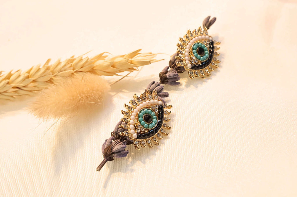Gold-tone mystic eye earrings featuring delicate craftsmanship, perfect for adding a meaningful touch to any outfit.