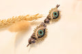 Gold-tone mystic eye earrings featuring delicate craftsmanship, perfect for adding a meaningful touch to any outfit.