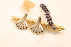 Close-up of seashell earrings, highlighting intricate gold accents and a delicate, ocean-inspired design.