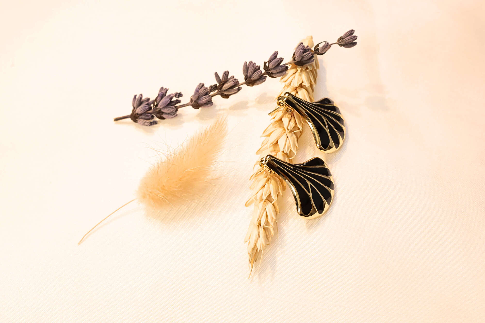 Gold-trimmed white seashell earrings placed on a soft backdrop, showcasing their refined and artistic details.