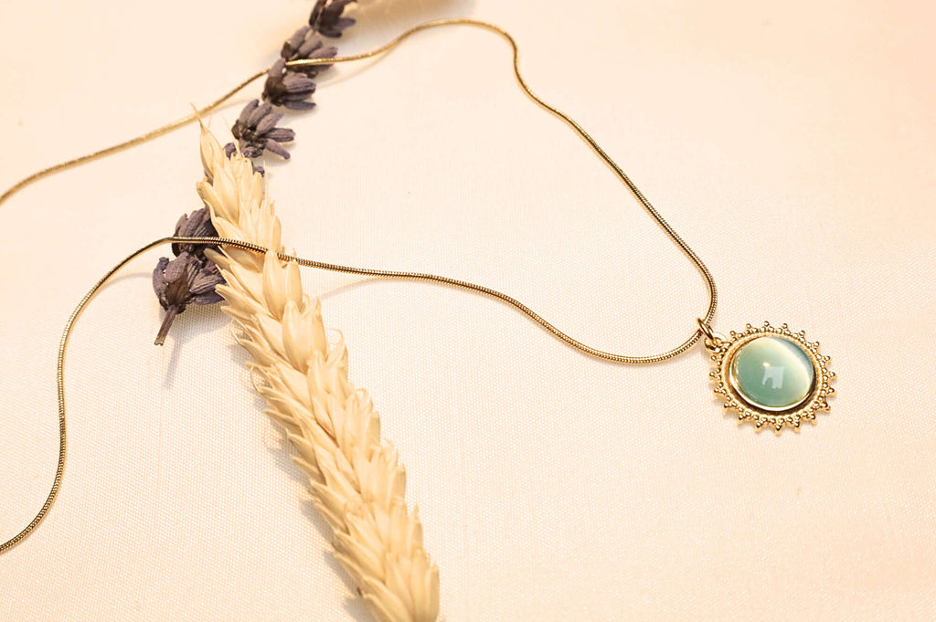 The turquoise sun pendant on a gold-plated chain, presented with a minimalistic and sophisticated aesthetic.