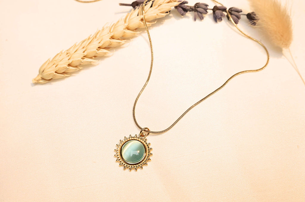 The elegant turquoise sun pendant, glowing under light with delicate stone details, captured in a natural setting.