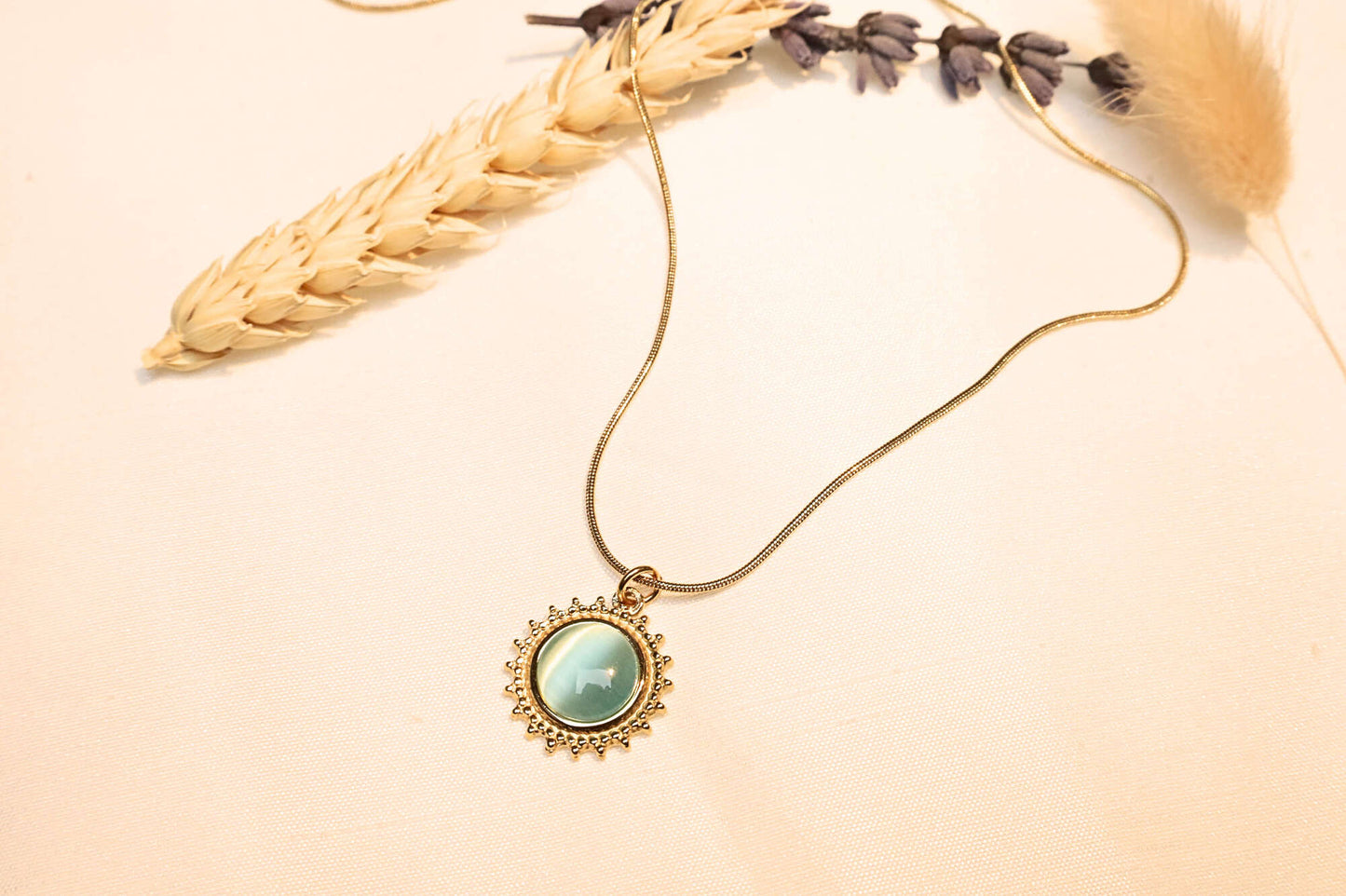 The elegant turquoise sun pendant, glowing under light with delicate stone details, captured in a natural setting.