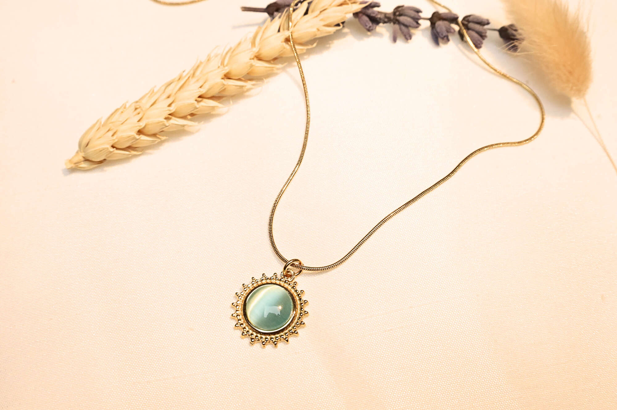 The elegant turquoise sun pendant, glowing under light with delicate stone details, captured in a natural setting.